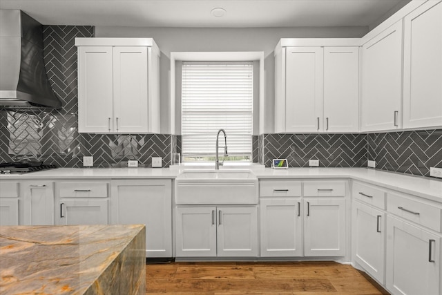 kitchen with white cabinetry, wall chimney exhaust hood, and sink