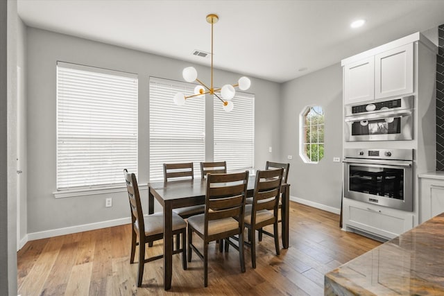 dining area featuring light wood-type flooring and an inviting chandelier