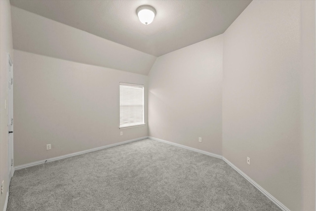 empty room featuring light carpet and vaulted ceiling