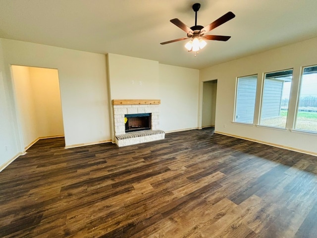 unfurnished living room with ceiling fan, dark hardwood / wood-style flooring, and a brick fireplace