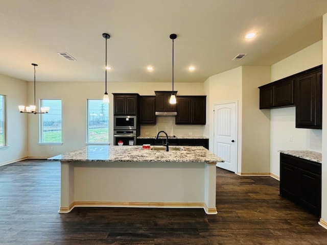 kitchen featuring sink, appliances with stainless steel finishes, dark hardwood / wood-style flooring, and a kitchen island with sink