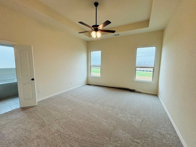 carpeted spare room featuring a raised ceiling and ceiling fan