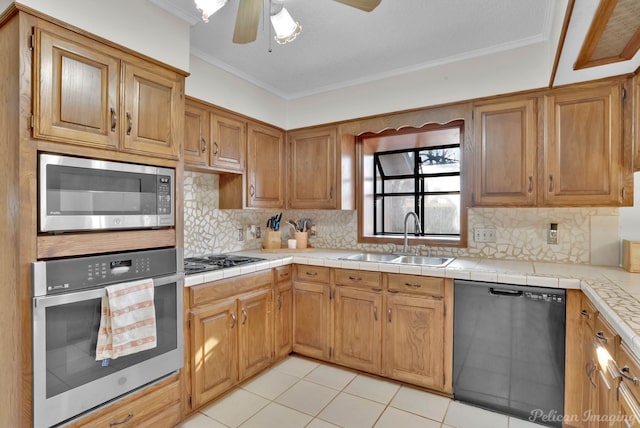 kitchen with ceiling fan, stainless steel appliances, tile counters, crown molding, and sink