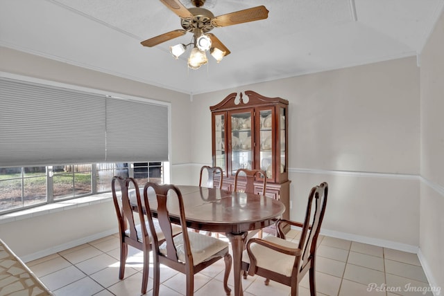 tiled dining area with ceiling fan and ornamental molding