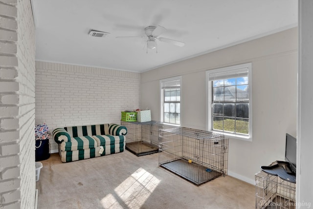 carpeted bedroom with ceiling fan and brick wall