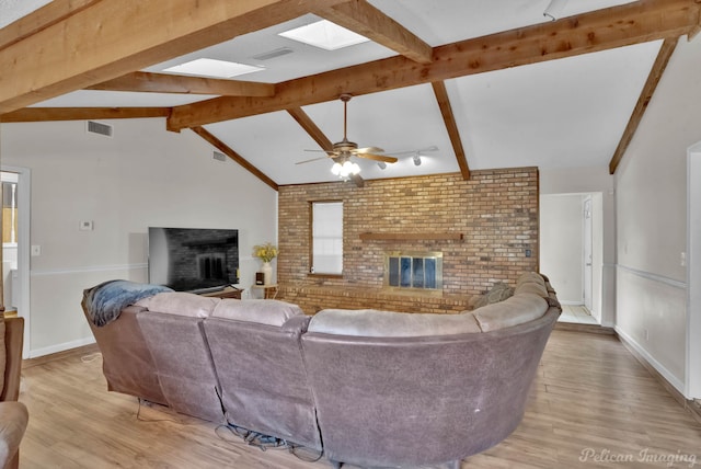 living room featuring a fireplace, light hardwood / wood-style floors, ceiling fan, and vaulted ceiling with beams