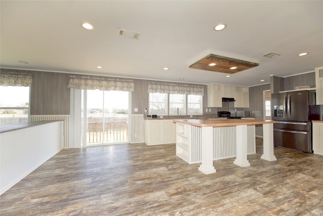 kitchen featuring refrigerator with ice dispenser, white cabinetry, wooden counters, and a center island