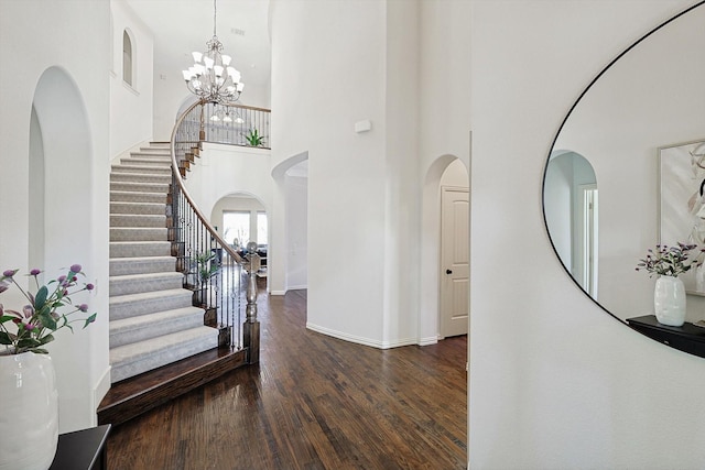 entrance foyer featuring an inviting chandelier, dark hardwood / wood-style floors, and a high ceiling