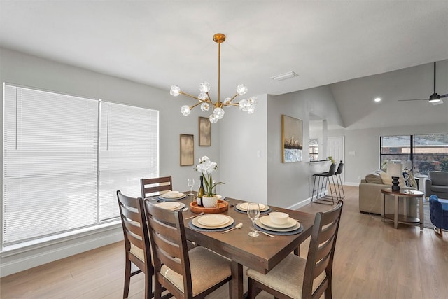 dining space featuring light wood-type flooring, lofted ceiling, and ceiling fan with notable chandelier