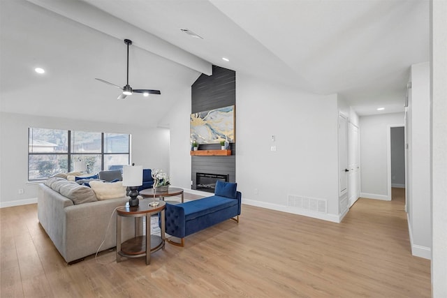 living room featuring light wood-type flooring, ceiling fan, a large fireplace, and vaulted ceiling with beams