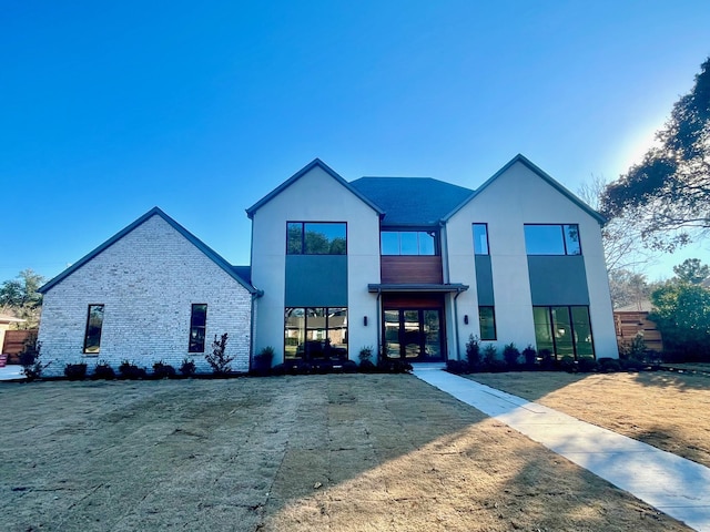 view of front of home featuring brick siding, a front lawn, and stucco siding