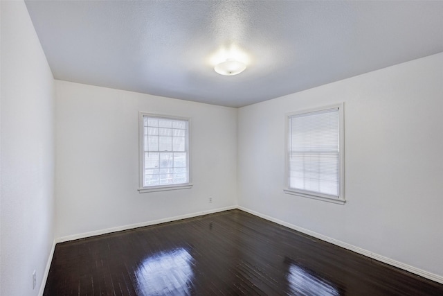 spare room with dark hardwood / wood-style floors and a textured ceiling