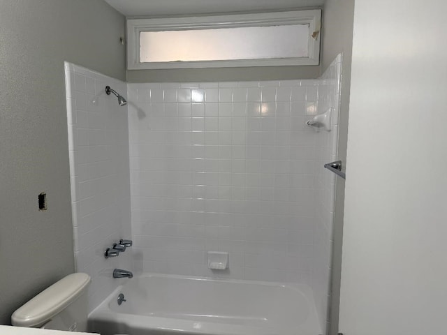 bathroom featuring toilet and tiled shower / bath