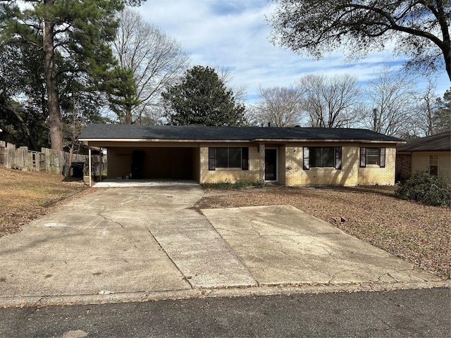 ranch-style house featuring an attached carport, brick siding, fence, and driveway