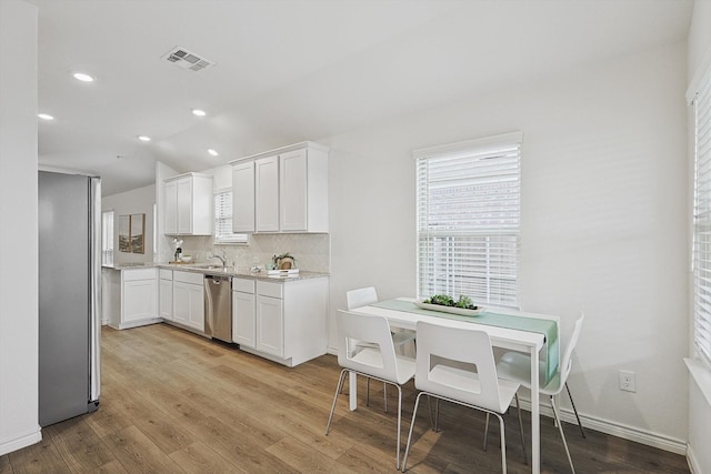 kitchen featuring light hardwood / wood-style flooring, decorative backsplash, stainless steel appliances, and white cabinetry