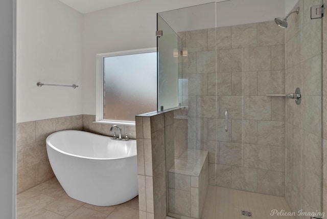 bathroom with shower with separate bathtub, tile patterned floors, and tile walls