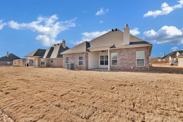 rear view of property with central air condition unit, a yard, and a patio