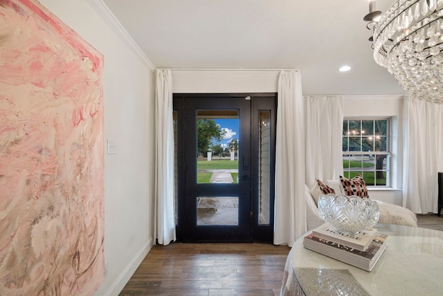 foyer featuring dark wood-type flooring, a chandelier, and crown molding