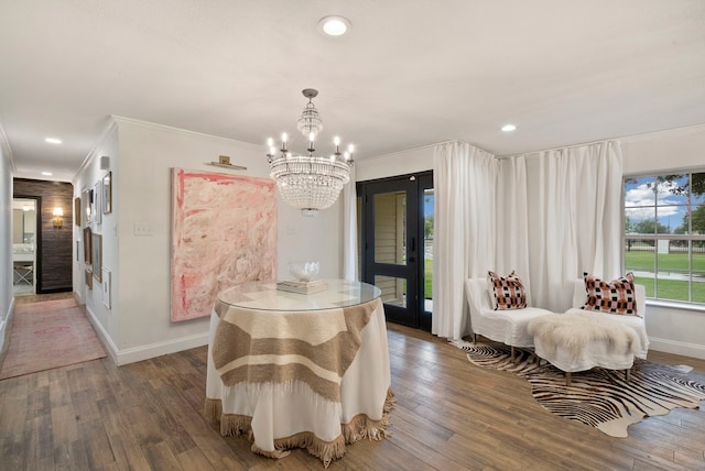 dining space featuring dark wood-type flooring, ornamental molding, and a notable chandelier