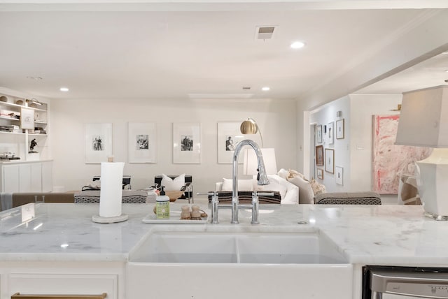 kitchen with white cabinets, sink, light stone counters, stainless steel dishwasher, and crown molding