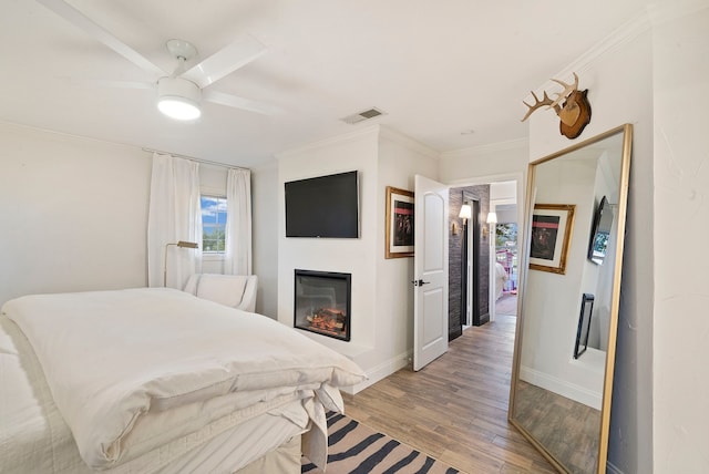 bedroom with ceiling fan, ornamental molding, and light wood-type flooring