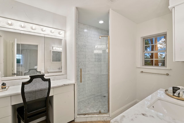 bathroom featuring a shower with door and vanity