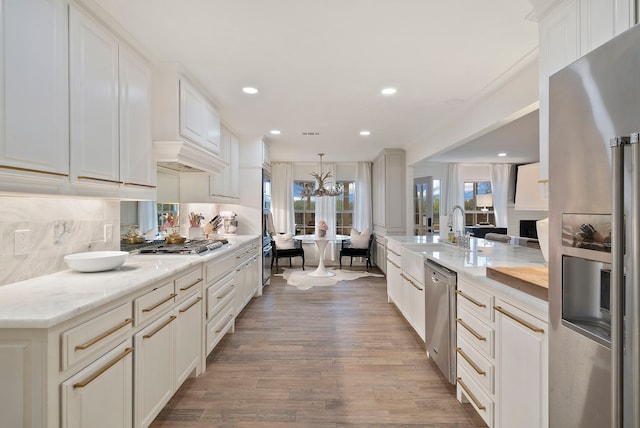 kitchen with tasteful backsplash, hardwood / wood-style floors, sink, hanging light fixtures, and stainless steel appliances