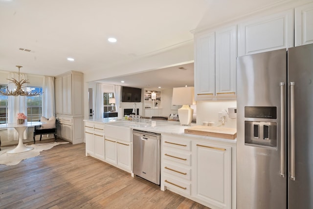 kitchen with stainless steel appliances, light wood-type flooring, light stone countertops, a chandelier, and pendant lighting