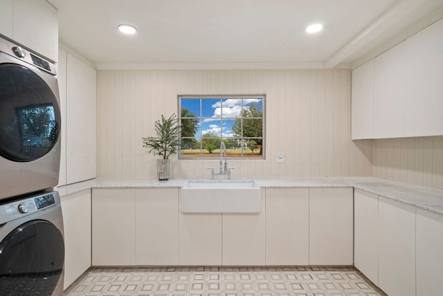 washroom featuring stacked washer / drying machine, sink, and cabinets