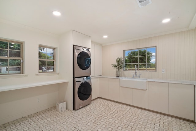 laundry area with stacked washer and dryer, sink, ornamental molding, and cabinets