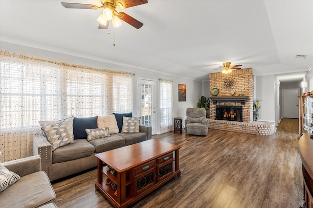 living room featuring visible vents, ceiling fan, vaulted ceiling, a fireplace, and wood finished floors