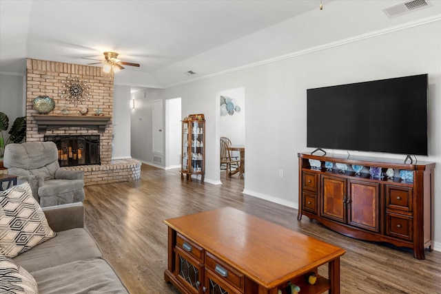 living room featuring ceiling fan, vaulted ceiling, a fireplace, wood-type flooring, and ornamental molding