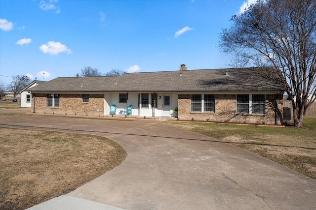 ranch-style house featuring brick siding, central AC unit, driveway, and a front lawn