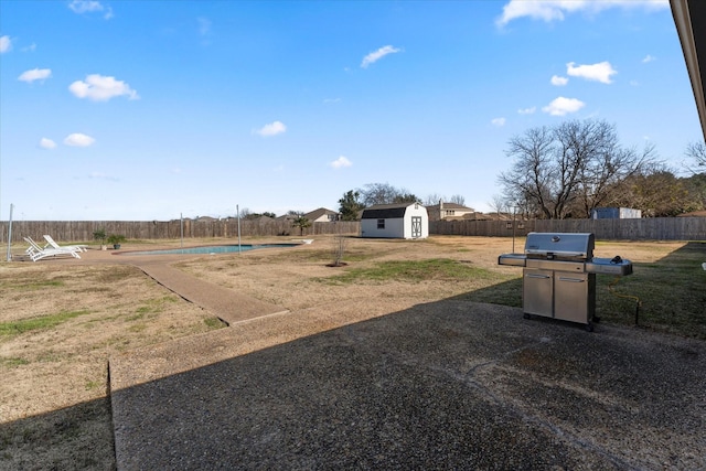 view of yard featuring a fenced in pool and a shed