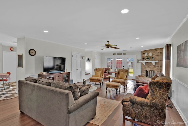 living room with ceiling fan, a fireplace, ornamental molding, and light hardwood / wood-style floors