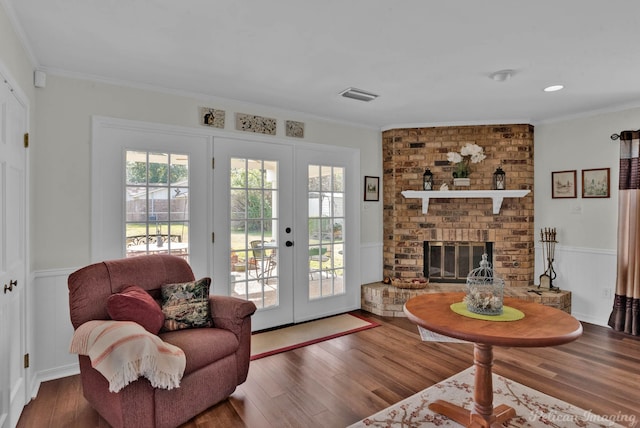 living room with french doors, a brick fireplace, and crown molding