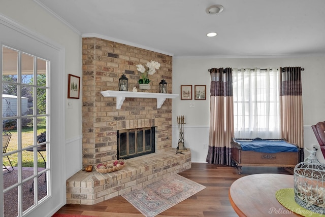 living room featuring hardwood / wood-style floors, crown molding, and a fireplace