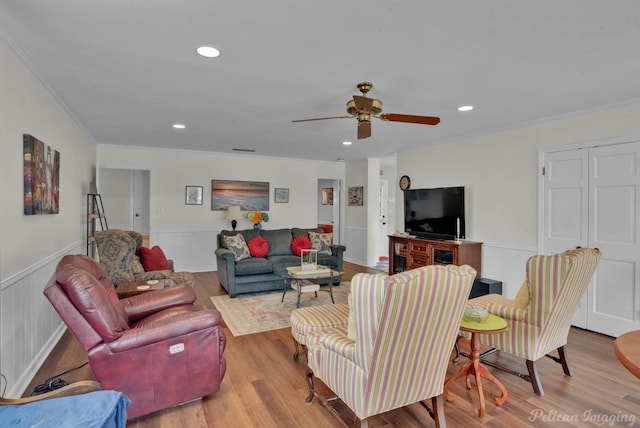 living room featuring ceiling fan, crown molding, and light hardwood / wood-style flooring