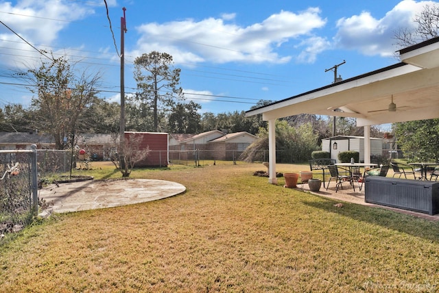 view of yard with ceiling fan, a storage shed, and a patio