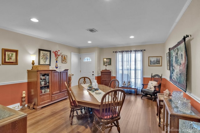 dining space featuring light wood-type flooring and ornamental molding