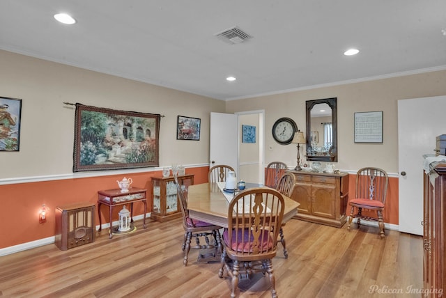 dining room with ornamental molding and light hardwood / wood-style flooring