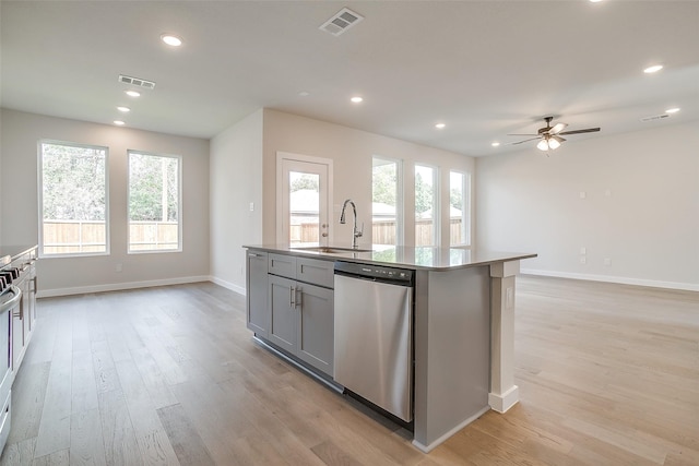 kitchen featuring sink, a center island with sink, gray cabinets, dishwasher, and a wealth of natural light