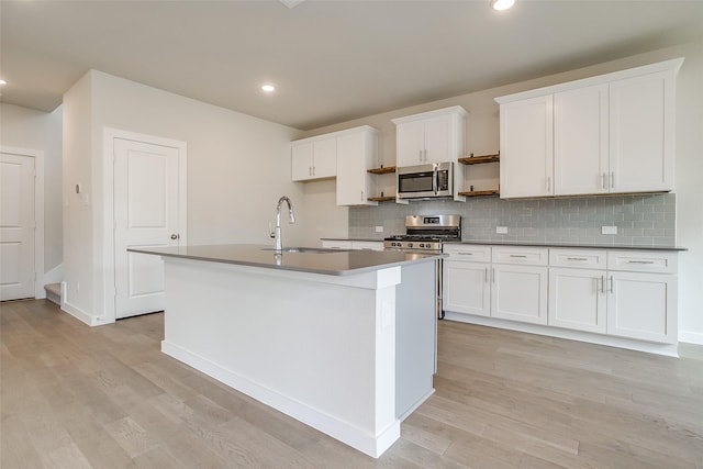 kitchen featuring sink, white cabinetry, stainless steel appliances, a kitchen island with sink, and decorative backsplash