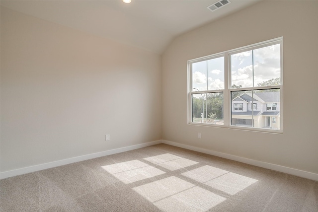 spare room featuring light colored carpet and vaulted ceiling