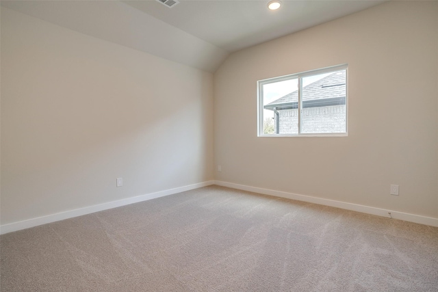 carpeted empty room with vaulted ceiling