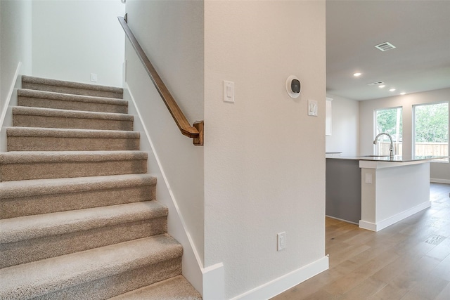 stairway featuring hardwood / wood-style flooring and sink