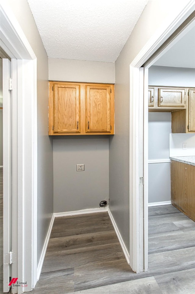 laundry area featuring a textured ceiling, cabinets, and dark hardwood / wood-style flooring