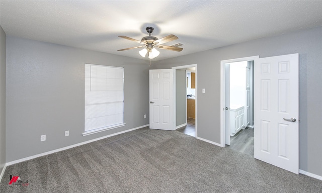 unfurnished bedroom with a textured ceiling, ceiling fan, ensuite bathroom, and carpet flooring