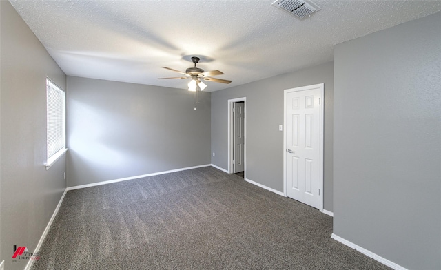 empty room with ceiling fan, dark carpet, and a textured ceiling