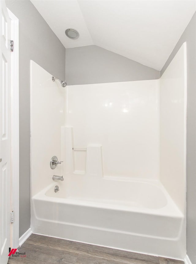 bathroom featuring lofted ceiling, hardwood / wood-style flooring, and shower / bathing tub combination